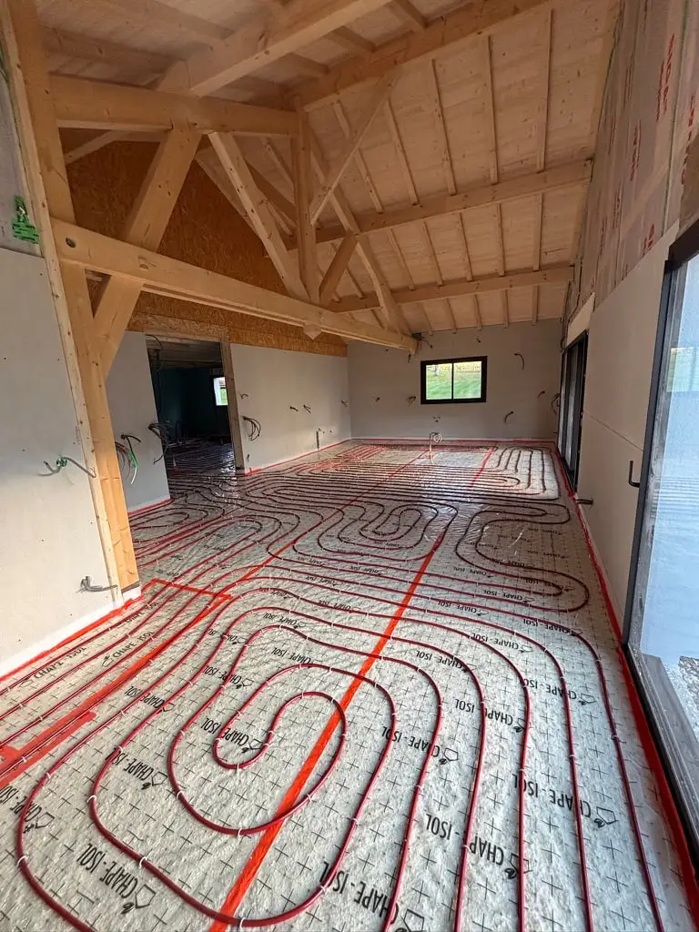 Plancher chauffant déroulé sur isolant dans une pièce sous charpente bois